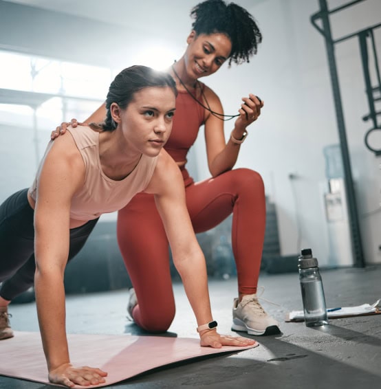 Personal trainer y chica haciendo flexiones.