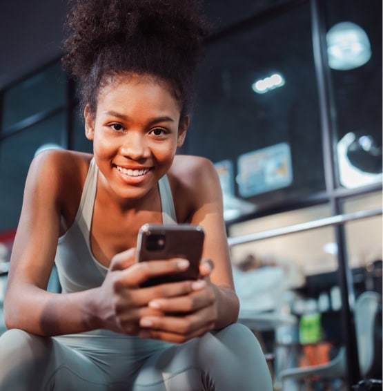 chica reiendo al recibir buenas noticias de su gym en el movil