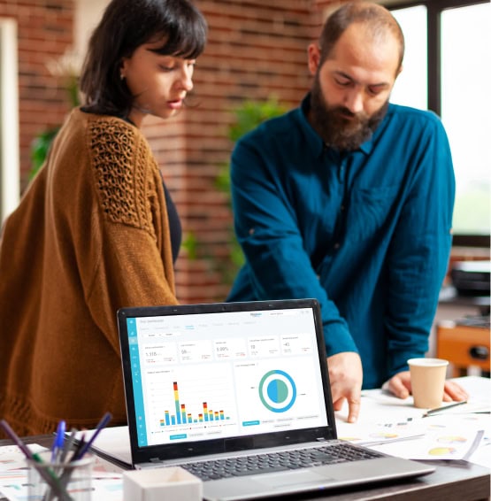 
Mujer y hombre mirando datos sobre la mesa con un laptop abierto con la web app de FitnessKPI.