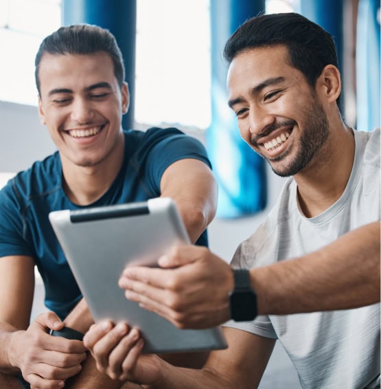 dos hombres comparten datos en un ipad dentro de un gimnasio