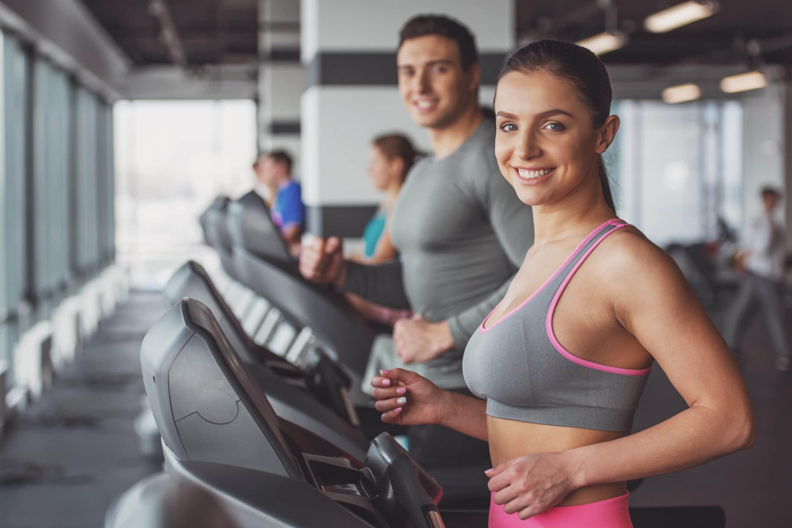 Satisfacción de cliente en el gimnasio: mujer sonriendo en la cinta ergométrica.